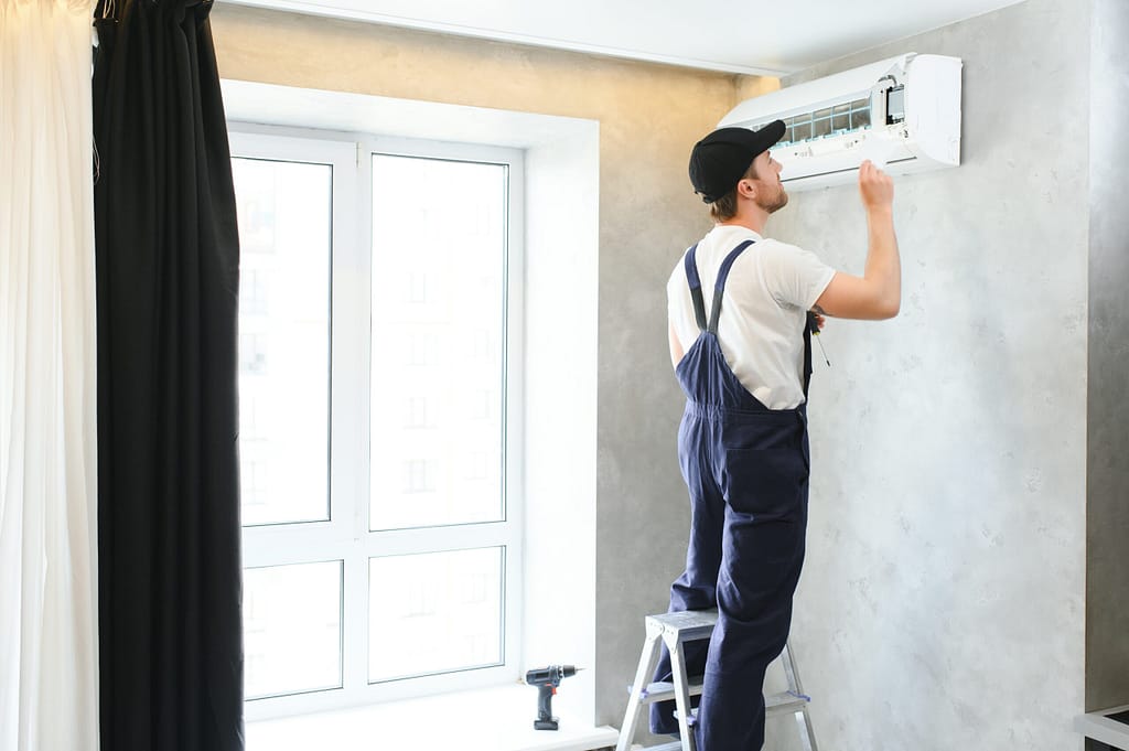 Male technician repairing an air conditioning unit in a New Jersey home.