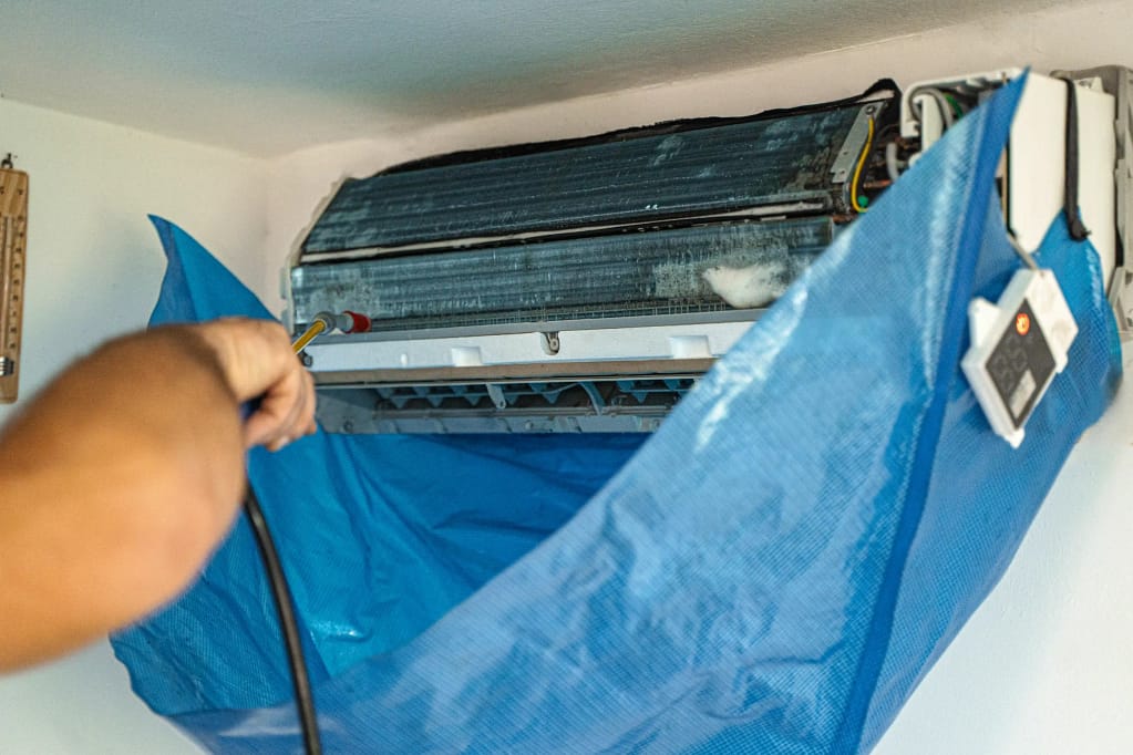 Technician cleaning air conditioning unit with protective cover in New Jersey home