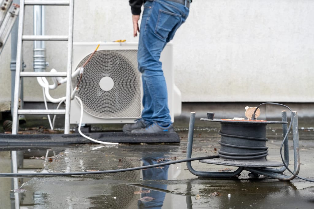 Person performing maintenance on an outdoor HVAC unit in New Jersey.