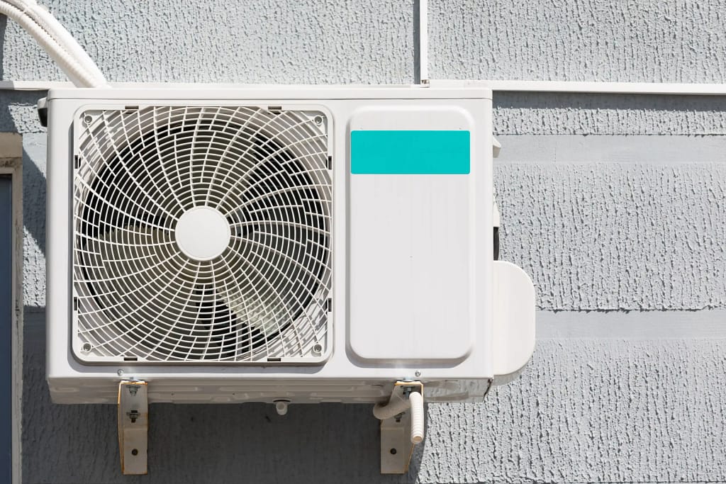 Outdoor air conditioning unit mounted on a building wall in New Jersey.