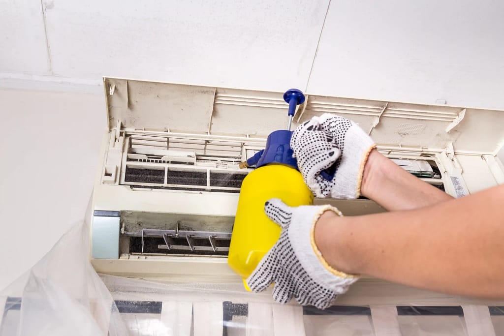 Technician cleaning air conditioning unit with chemical spray in New Jersey.