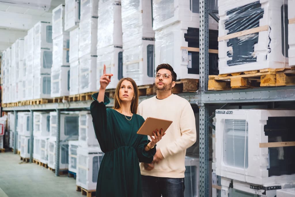 Warehouse workers inspecting inventory of HVAC units in a storage facility.