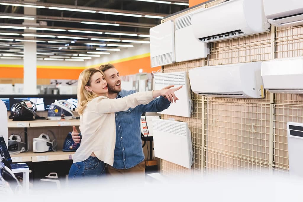 Couple pointing at HVAC units in a store, exploring cooling options.