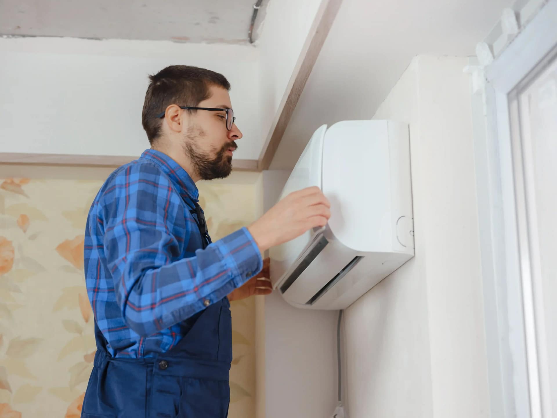 Technician adjusting a ductless AC unit during installation process.
